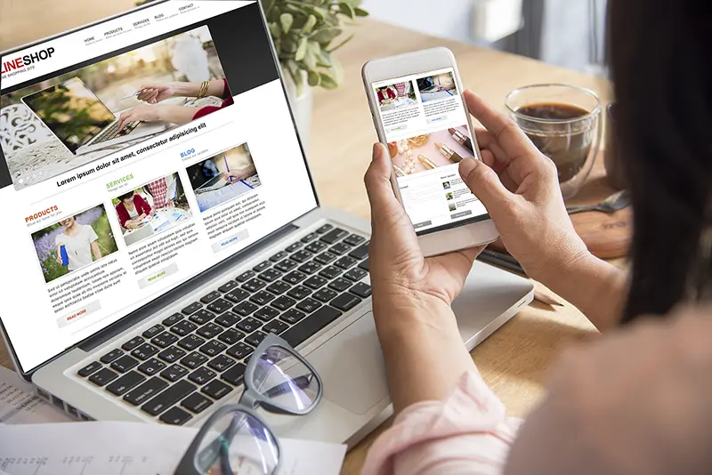 Woman checking website on laptop and mobile phone