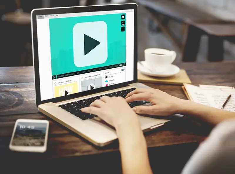 Woman using laptop with video play button on the screen