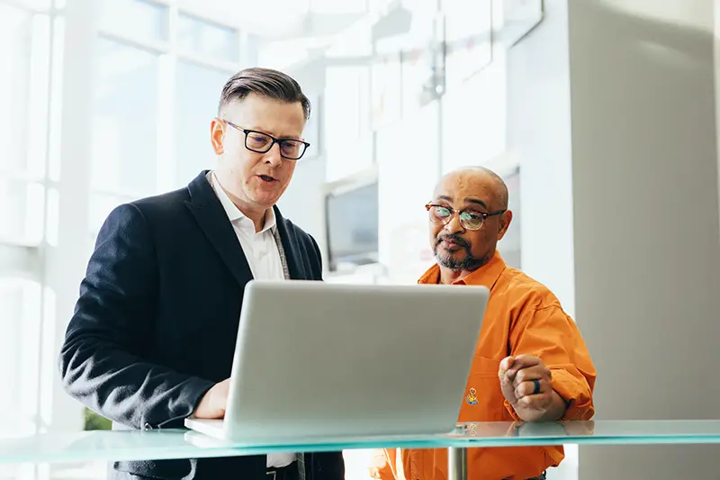 Man using silver laptop beside another man