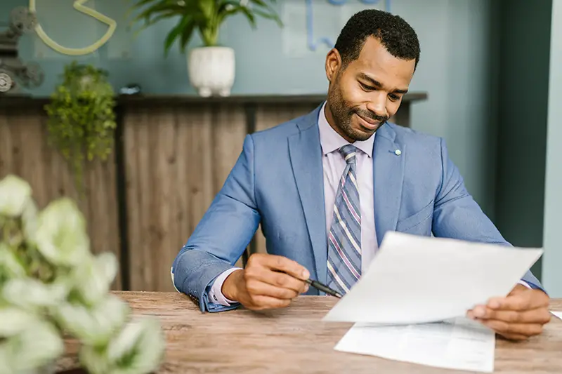 man in blue suite jacket holding white paper