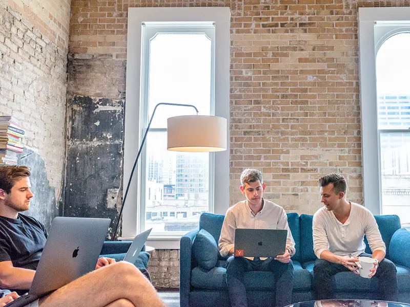 Three men sitting in the couch using laptop