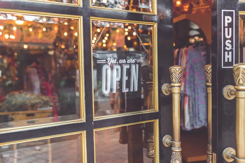 Close up photo of black door with signage yes we're open