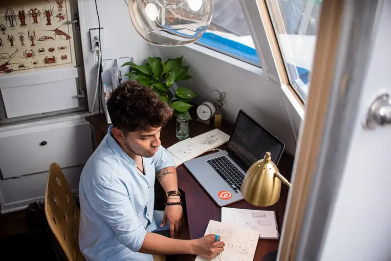 Man writing on his notepad in front of his desk