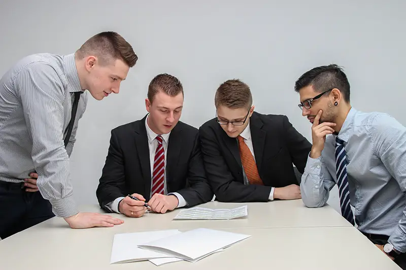 Four men looking to the paper on table