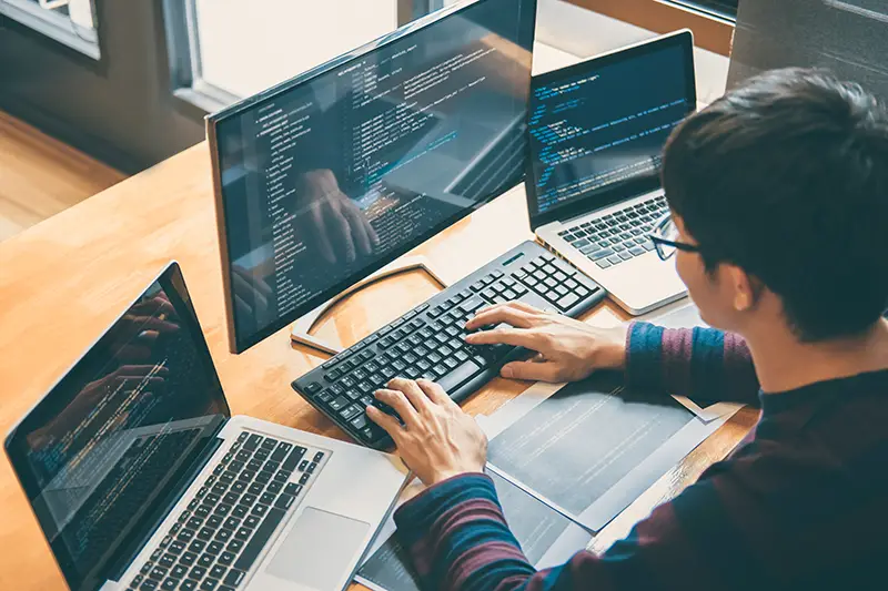 Person wearing eyeglasses working in front of laptop and computer