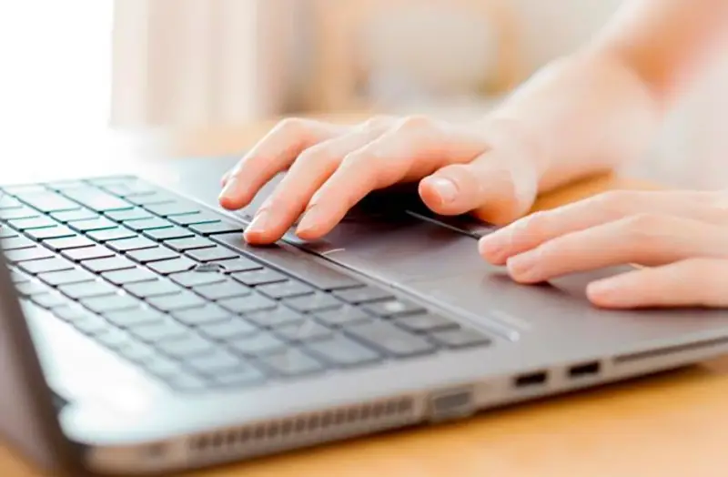 Cropped hand of person using laptop