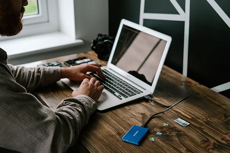 person in grey long sleeve shirt using MacBook air on brown table