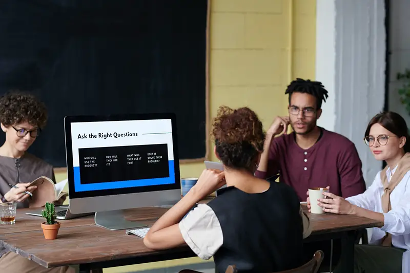 Four people talking near computer