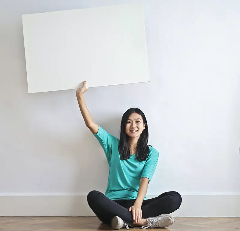 Smiling woman with blank poster in empty flat