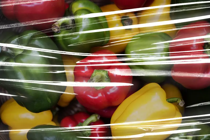 Fresh bell peppers covered with plastic wrap