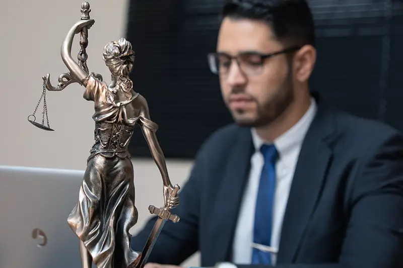 a lawyer behind a justice figure statue