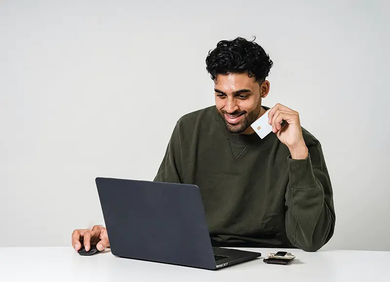 Man using laptop while holding a card for payment online