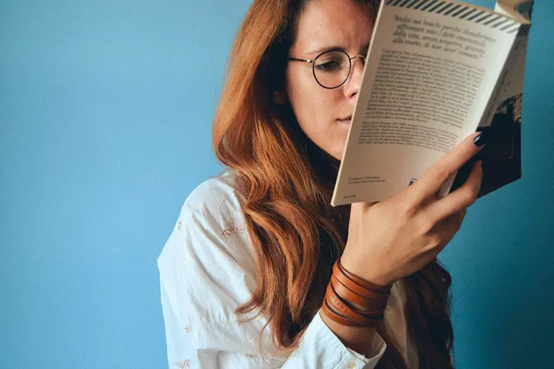 Woman wearing eyeglasses reading a book