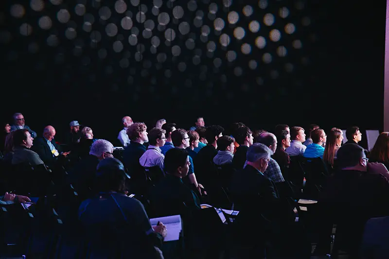 crowd of people sitting on chairs inside a room