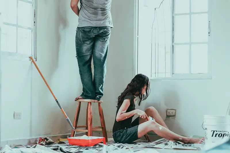 Man and woman painting the house wall
