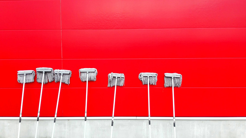 Cleaning mops leaning against a red wall