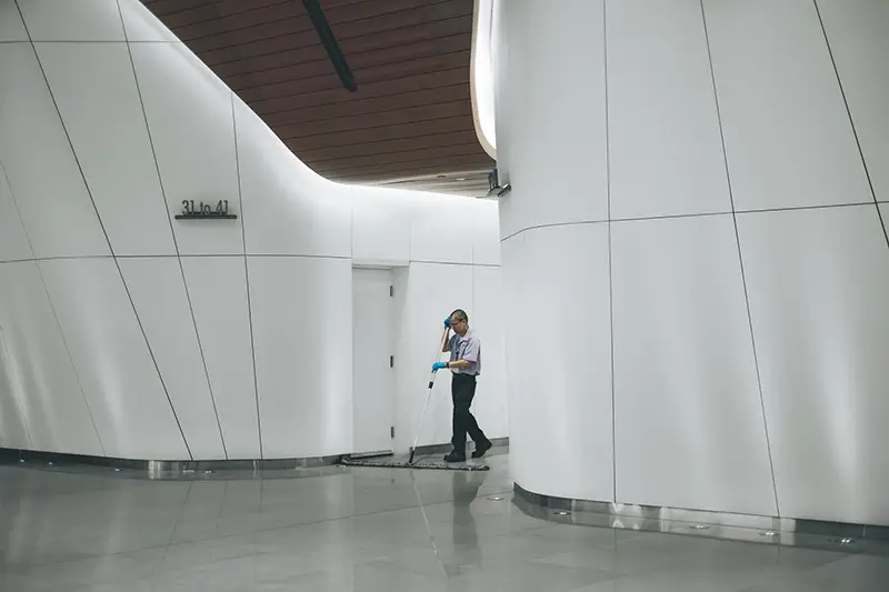 A male cleaner mops the floor in an office space