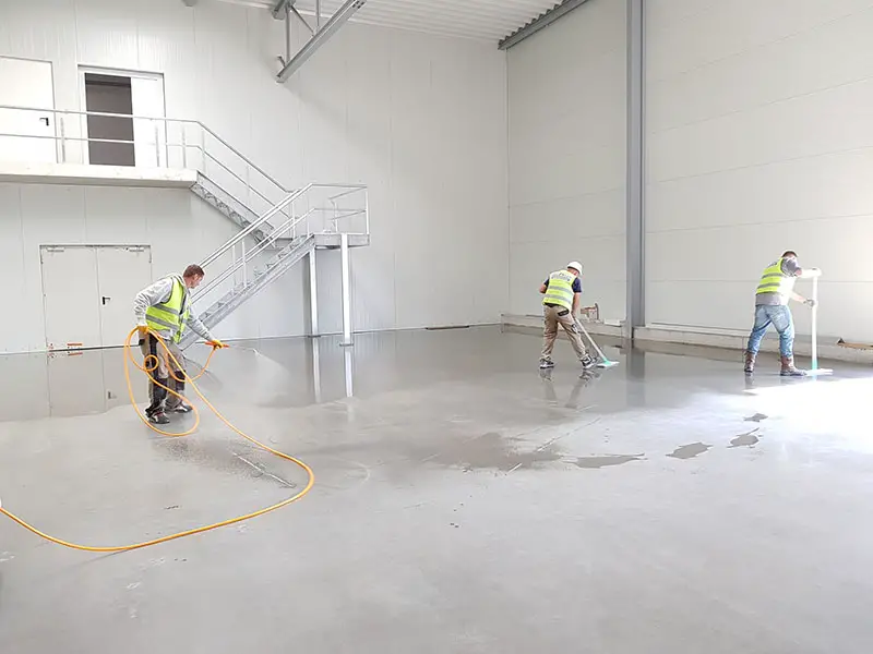 Workers wearing safety reflective vests cleaning the building floor