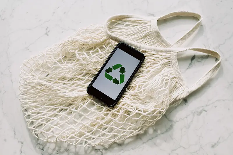 Mobile phone with green recycling symbol and mesh bag