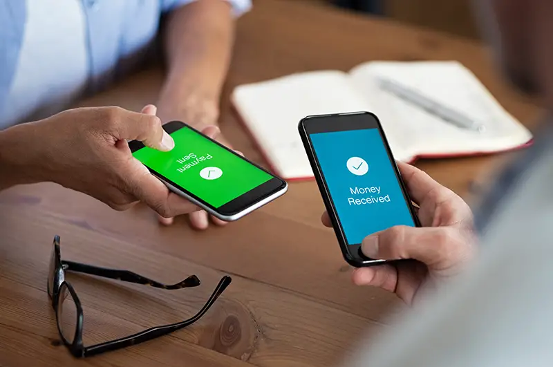 Closeup hands holding mobile phone with application for send and receive money. Man and woman holding smartphone and making payment transaction. Smart phone screen displaying payment sent.