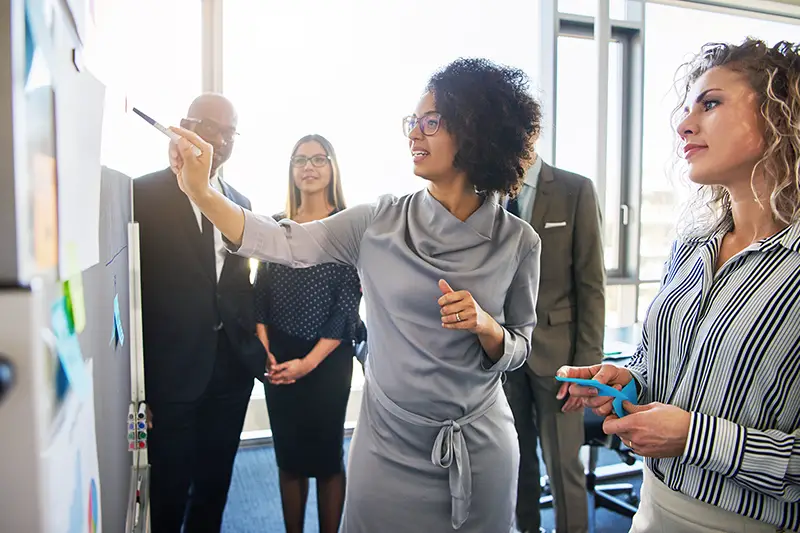 Diverse group of focused businesspeople brainstorming together on a whiteboard during a strategy session