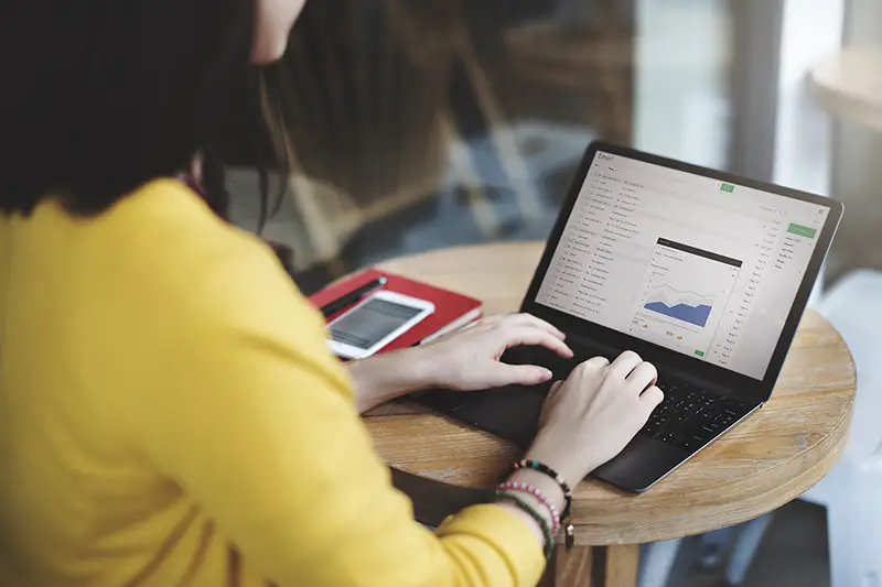 Woman wearing yellow blazer working on her laptop