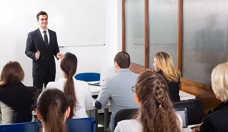 Group of attentive adult students with teacher in classroom at business training