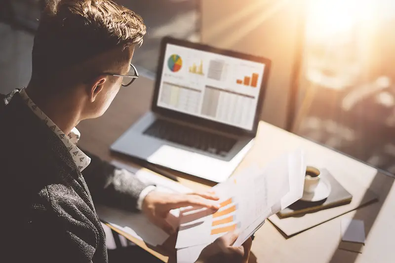 Young finance market analyst working at the office on laptop