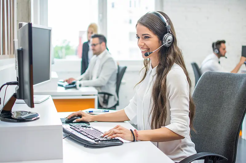 Smiling woman operator agent with headsets working in call center