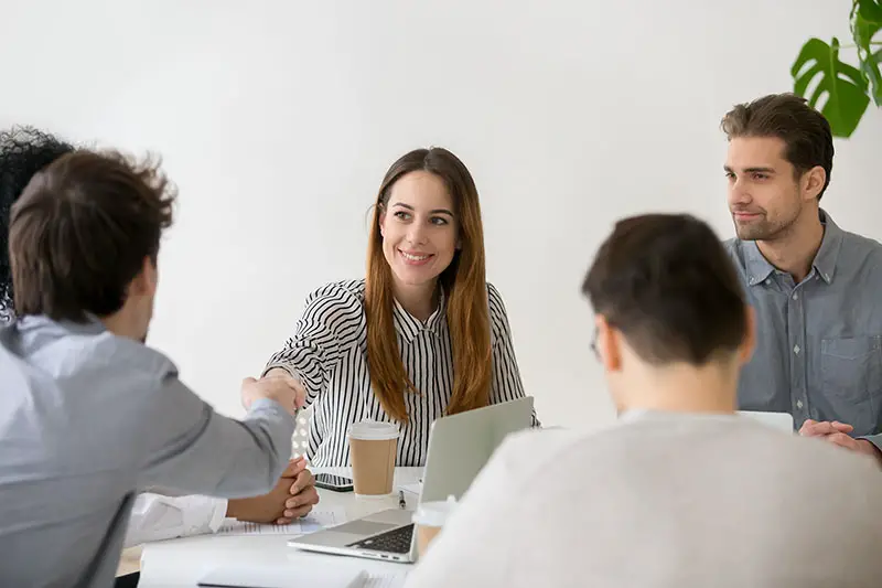 Smiling businesswoman shaking hand of male partner at the office meeting