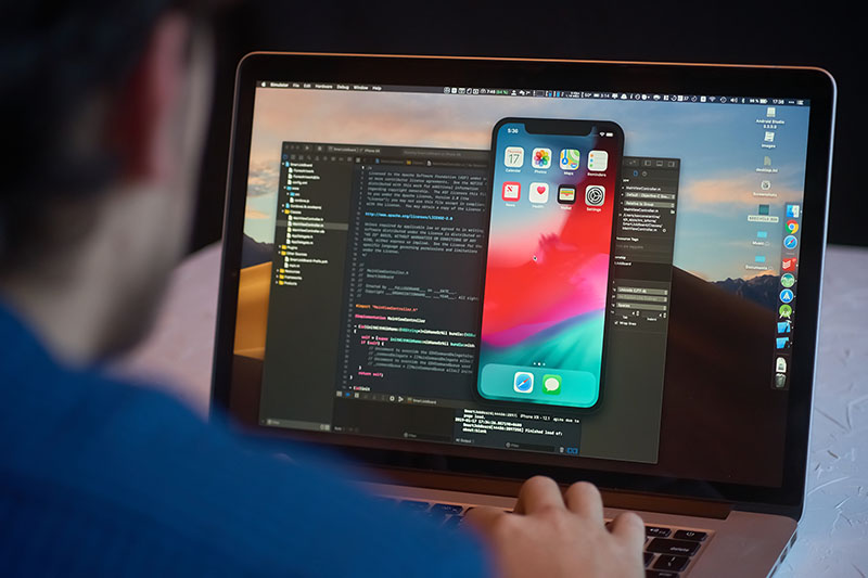 Man developer launches xcode software and ios simulator program to develop ios app on a MacBook