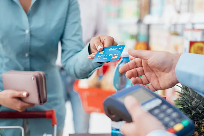 Woman at the supermarket checkout paying using a credit card