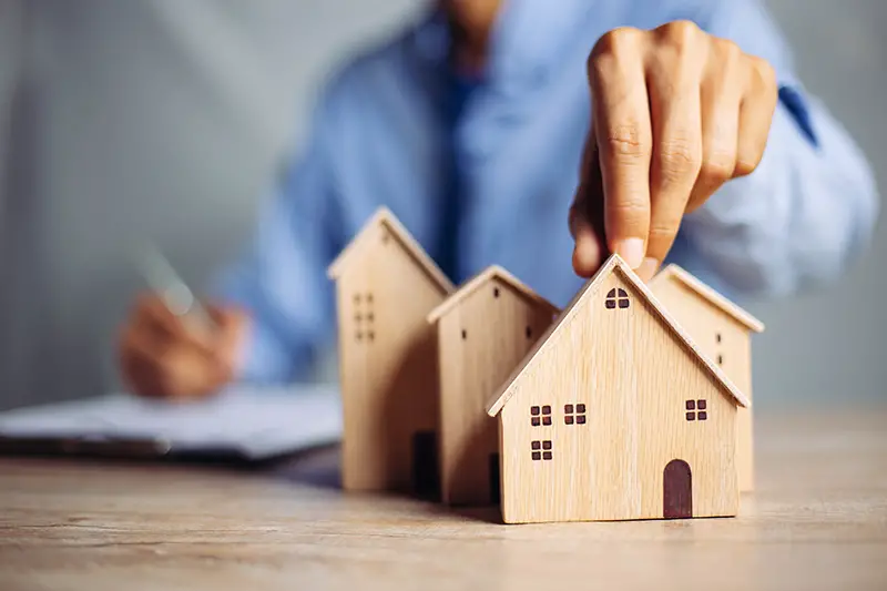 Businessman choosing mini wood house model