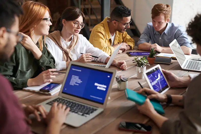 Group of diverse people working on their laptop on the top of brown wooden table