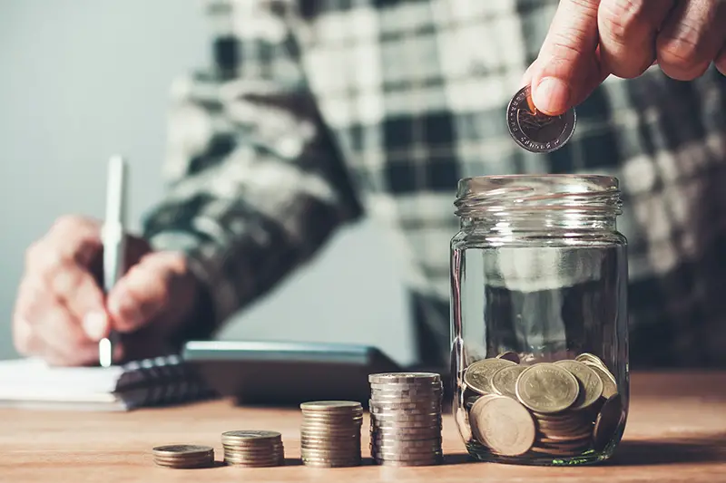 Business man putting coin in glass bottle saving bank