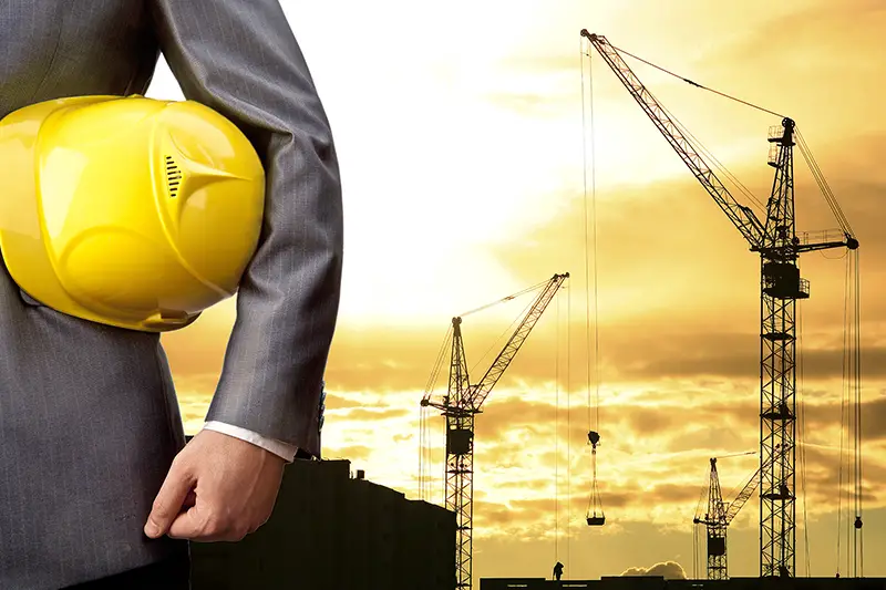Businessman holding yellow helmet with construction site  on the background