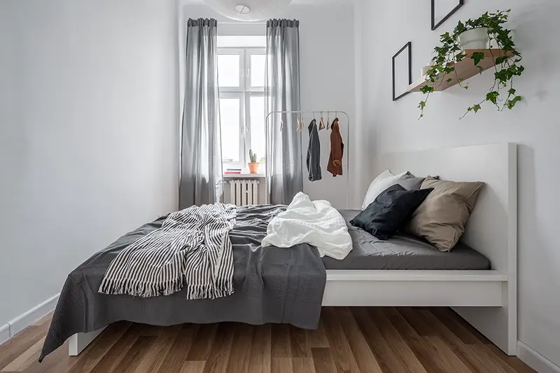 New bedroom with simple bed, clothes rack and wall shelf