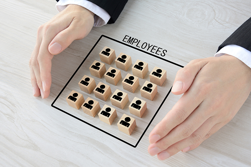 Wooden blocks with human pictogram surrounded by business man's hands