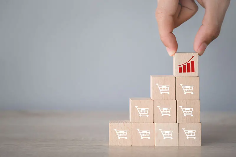 Hand arranging wood block stacking with icon Graph and shopping cart symbol