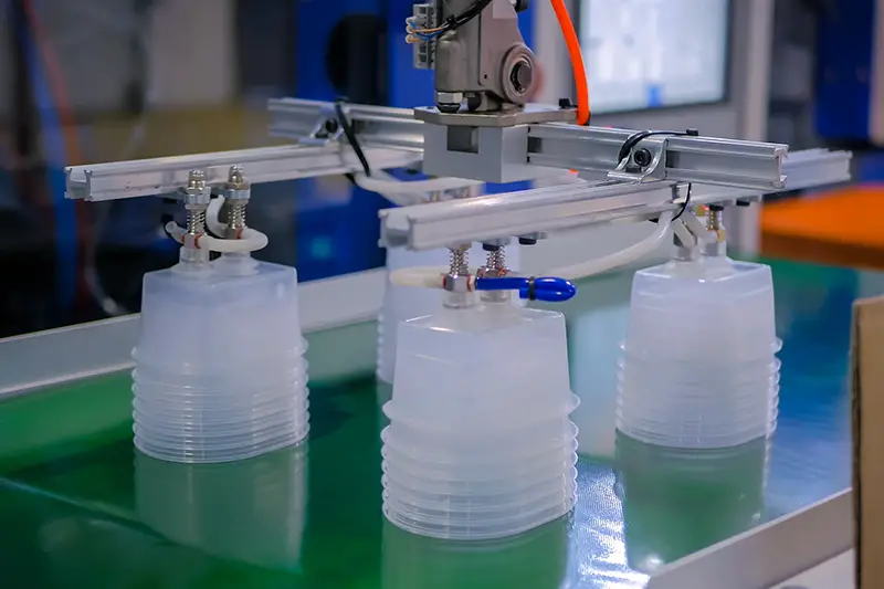 Stack of polypropylene food containers on conveyor belt of automatic plastic injection molding machine