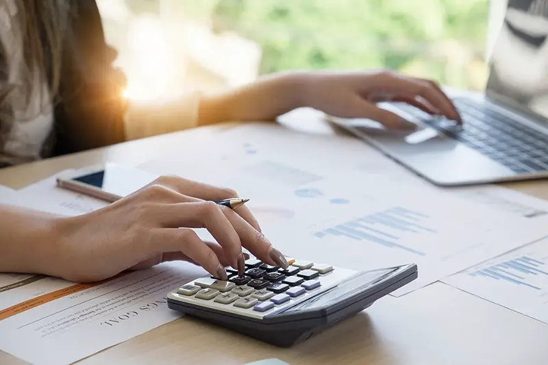 Close up Business woman using calculator and laptop for do math finance on wooden desk in office