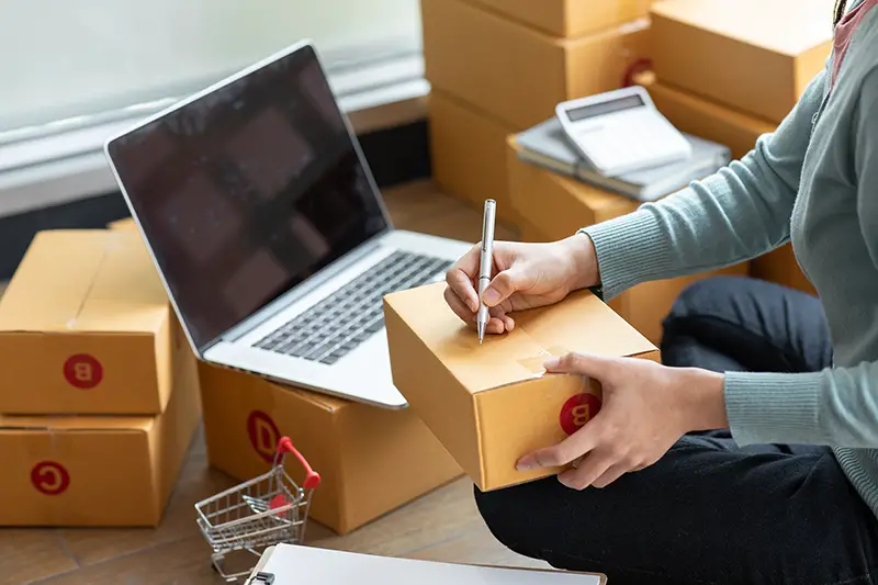 Woman writing on the brown package box