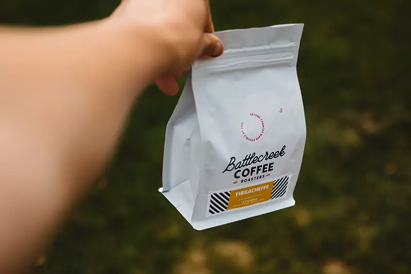 girl holding a white plastic pouch of coffee