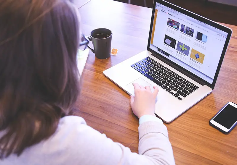 Woman working on her laptop near brown coffee mug