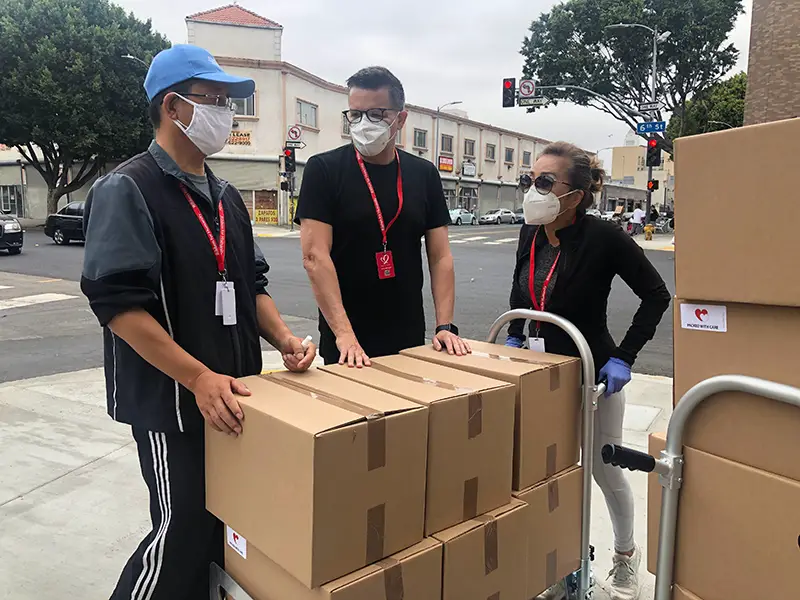 3 men in black shirt beside brown cardboard boxes