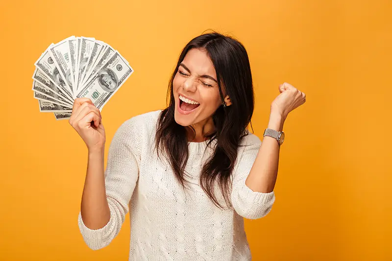 Portrait of a cheerful young woman holding money banknotes