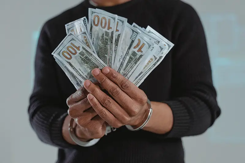 handcuffed man holding money bills