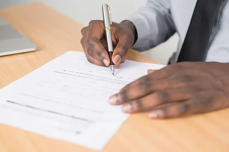 Person writing on a white piece of paper