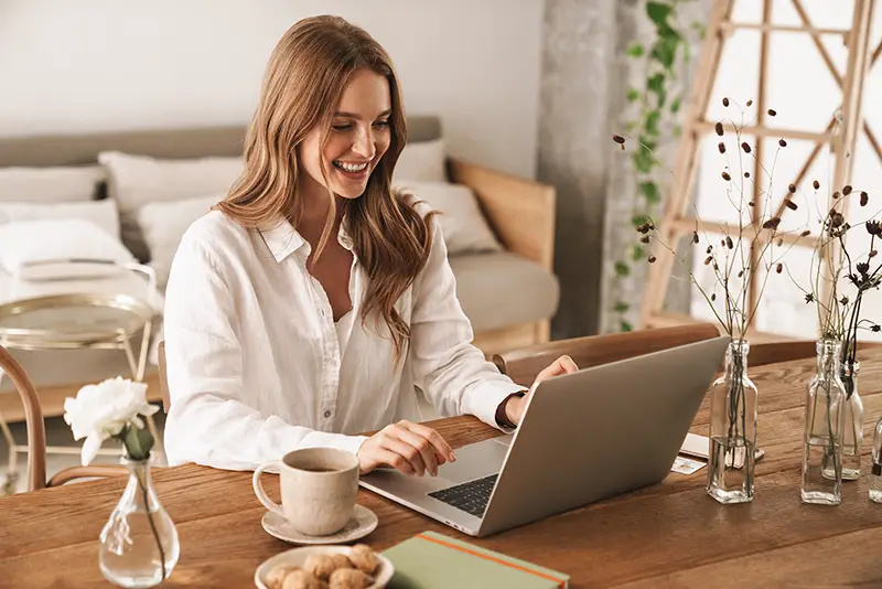 Young woman smiling while working on her laptop inside her home