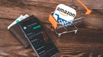 Black smartphone and wallet near amazon logo in shopping cart